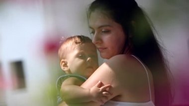 Beautiful mother holding hugging baby son outside balcony