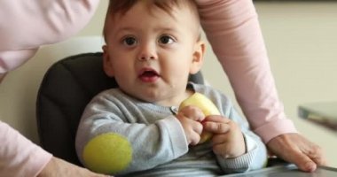 Casual candid family scene of parent putting meal table for baby to eat