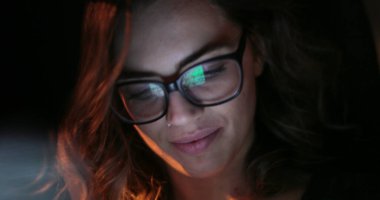 Young woman looking at cellphone in the back seat of a car. Girl wearing glasses riding taxi tab starring at tablet screen