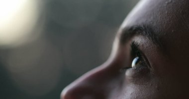 Young woman face opening and closing eyes. Girl meditating and in contemplation looking up to the sky with hope and faith