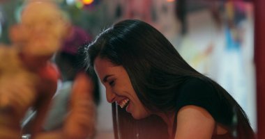 Night scene of Candid casual young women talking to person off-camera seen through restaurant window