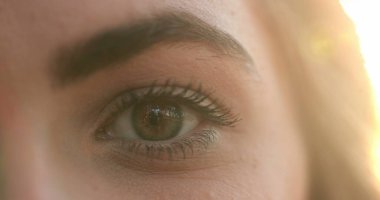 Macro close-up of young woman eyes in the sunlight with flare, opening and closing eyes meditating and contemplation