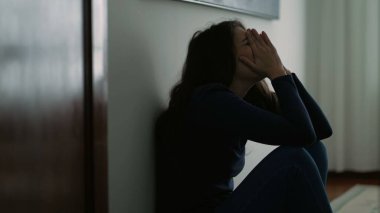 Kadın duygusal bir acı hissediyor evde oturmuş çaresiz bir şekilde utançla yüzünü kapatıyor.