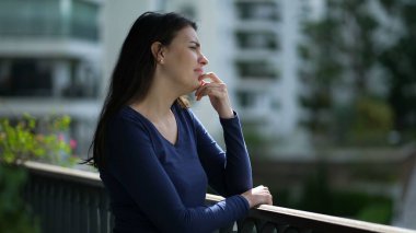 Düşünceli bir kadın apartmanın balkonunda durup düşünüyor. Çözüm arayan düşünceli kişi