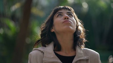 Güney Amerikalı genç bir kadın gökyüzüne bakıyor. Düşünceli bir İspanyol kız dışarıda duruyor.