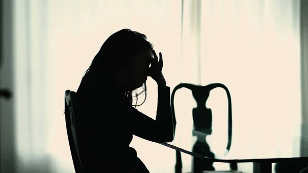 Silhouette of suffering woman sitting at home in mental pain