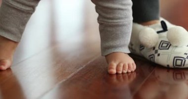 Baby toddler feet on hardwood floor indoor home learning to stand-up