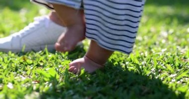 Baby first steps outside in nature, toddler infant learning to walk