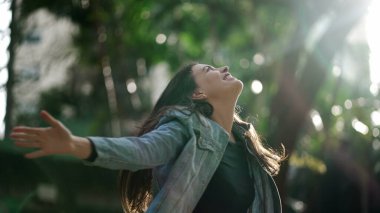 Heyecanlı kadın doğadaki yaşamı kutlayan kollarını kaldırıyor. Mutlu insan kollarını açmış gülümsüyor ve seviniyor.