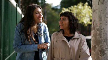 Sokakta yürürken kadınlar konuşuyor. Şehir kaldırımında sohbet eden iki kız arkadaş.