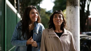 Sokakta yürürken kadınlar konuşuyor. Şehir kaldırımında sohbet eden iki kız arkadaş.