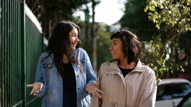 Sokakta yürürken kadınlar konuşuyor. Şehir kaldırımında sohbet eden iki kız arkadaş.