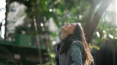 Heyecanlı kadın doğadaki yaşamı kutlayan kollarını kaldırıyor. Mutlu insan kollarını açmış gülümsüyor ve seviniyor.