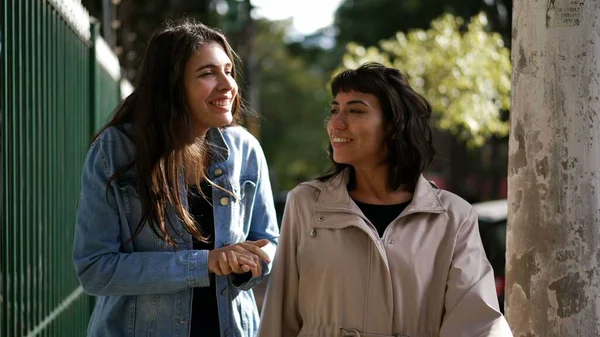 Sokakta yürürken kadınlar konuşuyor. Şehir kaldırımında sohbet eden iki kız arkadaş.