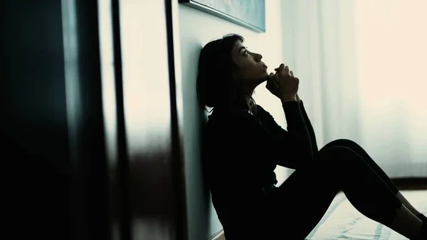 Wounded person sitting on floor praying for help. One hispanic girl prays to God seeking guidance