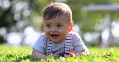 Adorable baby laid on grass in outdoors nature smiling and laughing