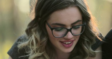 Portrait of blonde hispanic girl wearing glasses studying outside reading