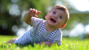 Happy baby child smiling in outdoor lying on grass