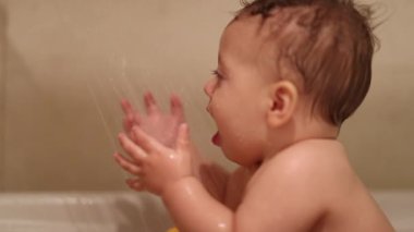 Showering baby boy, cleaning toddler, bathing child inside bathtub
