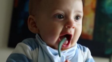 Cute baby playing with spoon. Playful toddler holding spoon during lunch