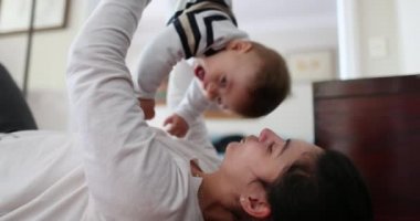 Mother playing with baby boy son. Mom lifting upside down toddler. Happy infant laughing and smiling