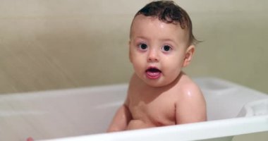 Bathing cute baby. Washing adorable toddler inside bathtub