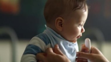 Mother feeding happy baby. Parent trying to feed excited toddler meal