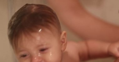 Washing baby face, mother showering toddler boy. Mom cleaning infant child