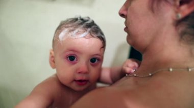 Authentic mother and baby child together in shower. Casual bathing infant