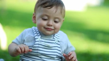 Cute baby child in outdoor park touching grass
