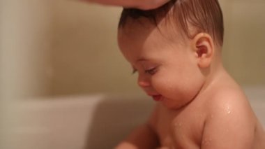 Toddler baby inside bathtub holding yellow duck