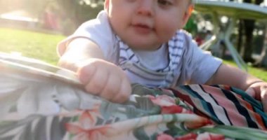Happy baby laughing holding into mother laid on grass outside