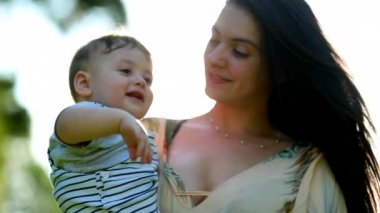 Mother holding baby son in outdoor with sunlight lens-flare sunshine