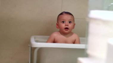 Bathing adorable baby inside bathtub, washing cute infant boy