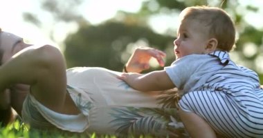 Casual candid mother and baby together laid on grass