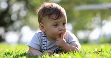 Beautiful cute baby laid on grass outside in nature smiling