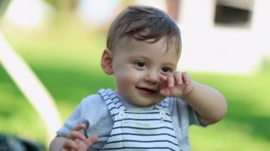 Cute baby boy rubbing eye in outdoor park