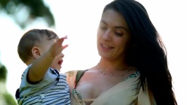 Candid mother and baby together clapping hands in outdoor nature