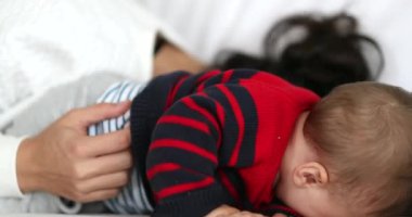 Mom and baby son together in sofa home in playful authentic candid scene