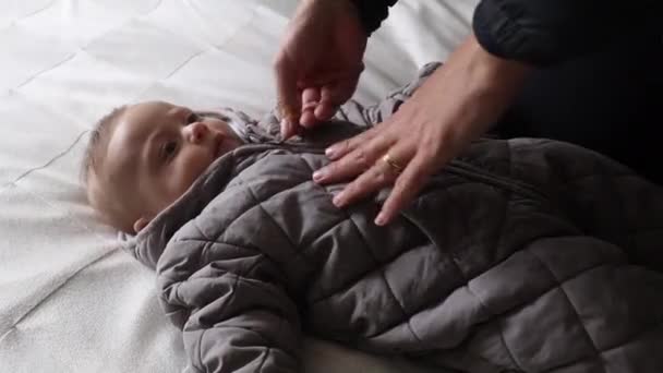 Parent Unzipping Baby Wearing Winter Clothing Lying Bed — Video Stock