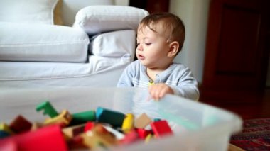 Baby playing with toys in room holding in box container grabbing toy
