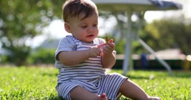 Child baby toddler seated outside in grass exploring world