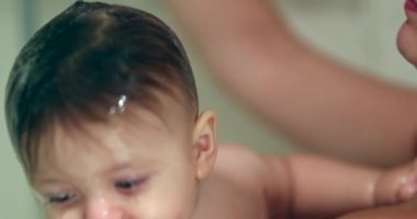 Mother showering toddler boy. Washing baby face