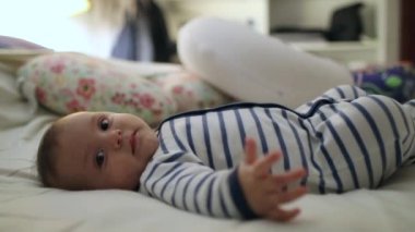 Newborn cute baby laid in bed looking to camera