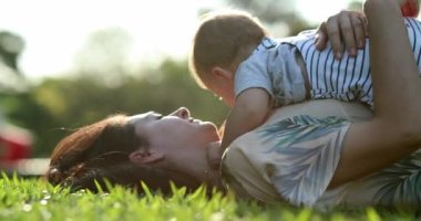 Candid mother and baby together laid in grass
