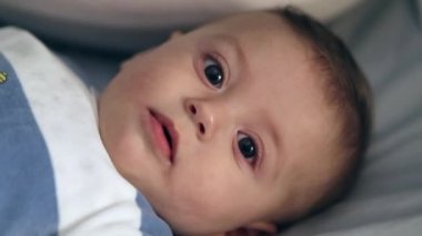 Sweet baby laid in bed looking to camera with surprise