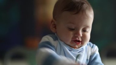 Cute baby toddler biting spoon. Parent feeding happy infant baby