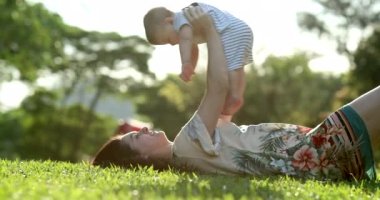 Mother and baby together outside in nature during sunset laid on grass outdoors