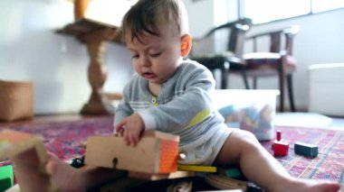 Baby playing with toy indoors, close-up face of toddler