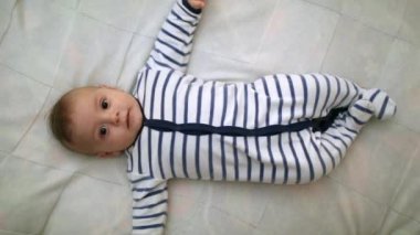 Adorable toddler baby laid in bed looking to camera